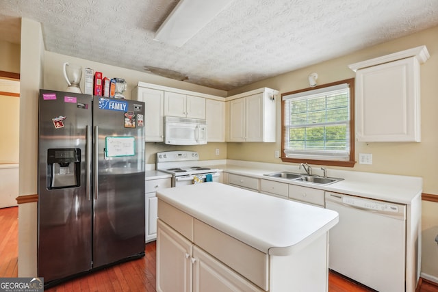 kitchen with white cabinets, hardwood / wood-style flooring, a center island, white appliances, and sink