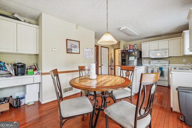 dining room with a textured ceiling, dark wood-type flooring, and sink