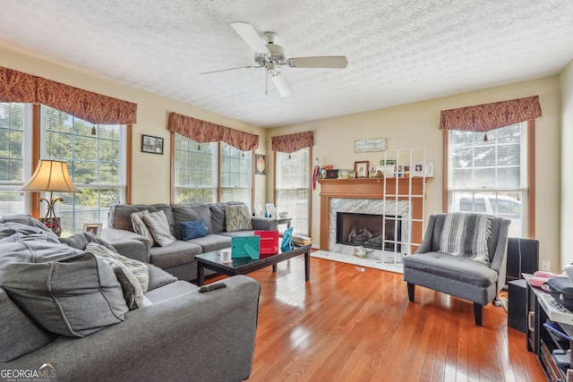 living room with a textured ceiling, ceiling fan, hardwood / wood-style flooring, and a fireplace