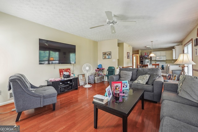 living room featuring a textured ceiling, wood-type flooring, and ceiling fan