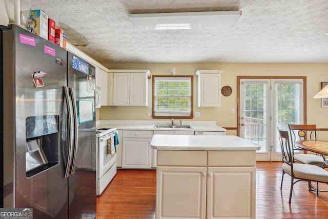 kitchen with light hardwood / wood-style flooring, white appliances, white cabinetry, sink, and a textured ceiling