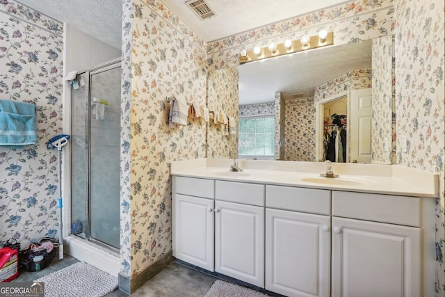 bathroom featuring tile patterned floors, an enclosed shower, a textured ceiling, and vanity