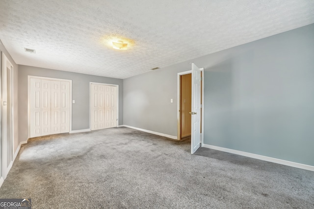 carpeted empty room featuring a textured ceiling