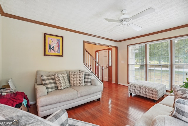 living room featuring a textured ceiling, crown molding, ceiling fan, and wood-type flooring