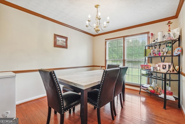 dining room featuring crown molding, a textured ceiling, hardwood / wood-style floors, and a notable chandelier