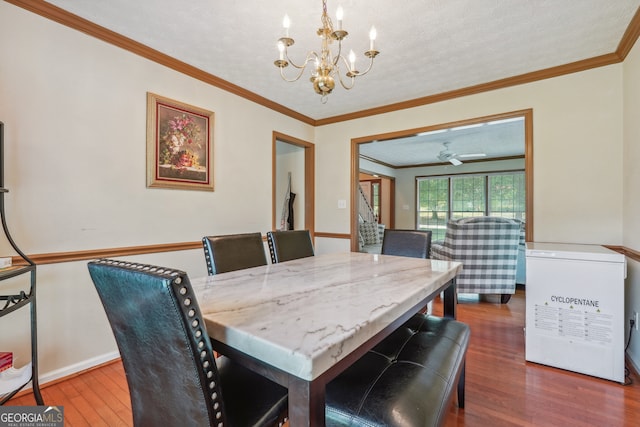 dining space with crown molding, a textured ceiling, hardwood / wood-style floors, and an inviting chandelier