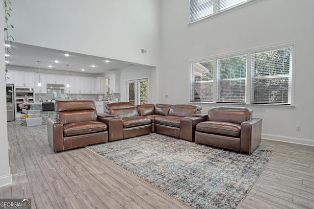 living room with light hardwood / wood-style flooring and a towering ceiling