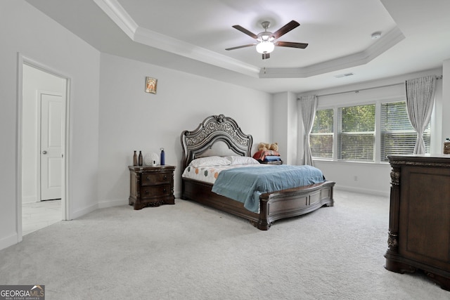 bedroom featuring crown molding, a tray ceiling, light carpet, and ceiling fan