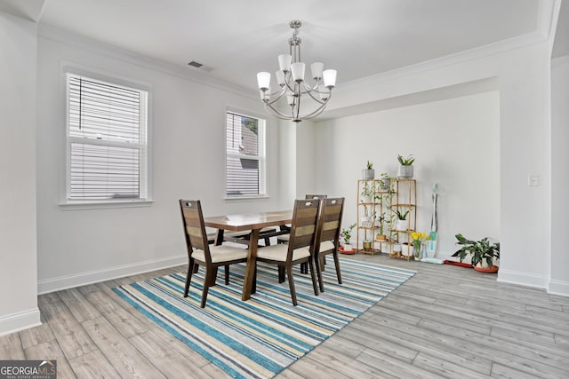 dining room featuring light wood-type flooring, crown molding, and a chandelier