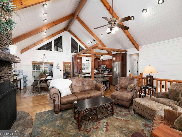 living room with high vaulted ceiling, wood walls, ceiling fan, hardwood / wood-style flooring, and beam ceiling