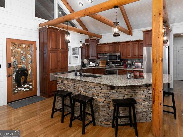 kitchen with appliances with stainless steel finishes, a kitchen bar, and hanging light fixtures