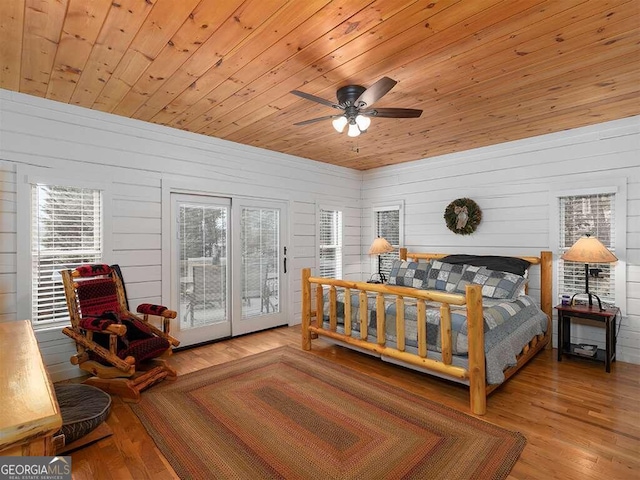 bedroom with wooden walls, light hardwood / wood-style flooring, access to exterior, ceiling fan, and wooden ceiling