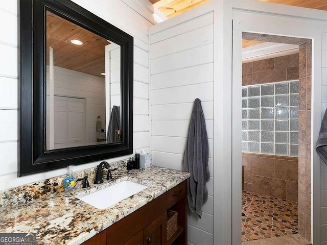 bathroom with wood ceiling, vanity, and walk in shower