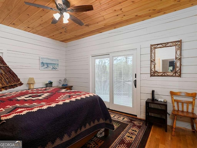 bedroom with wood walls, wood-type flooring, wood ceiling, access to exterior, and ceiling fan