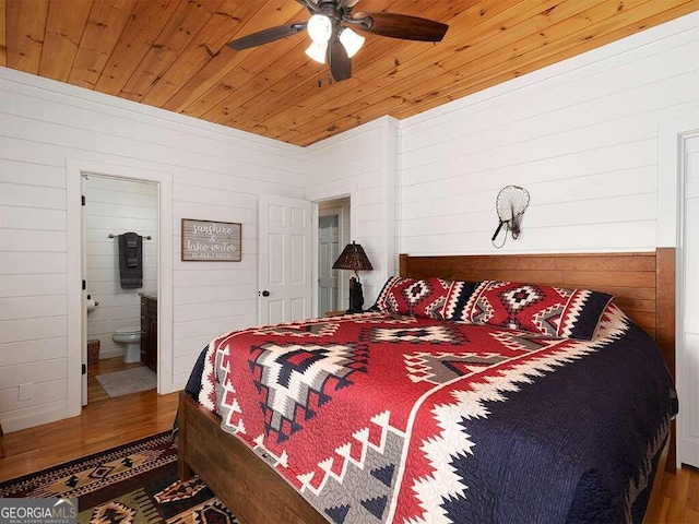 bedroom with hardwood / wood-style floors, wood walls, ensuite bath, ceiling fan, and wooden ceiling