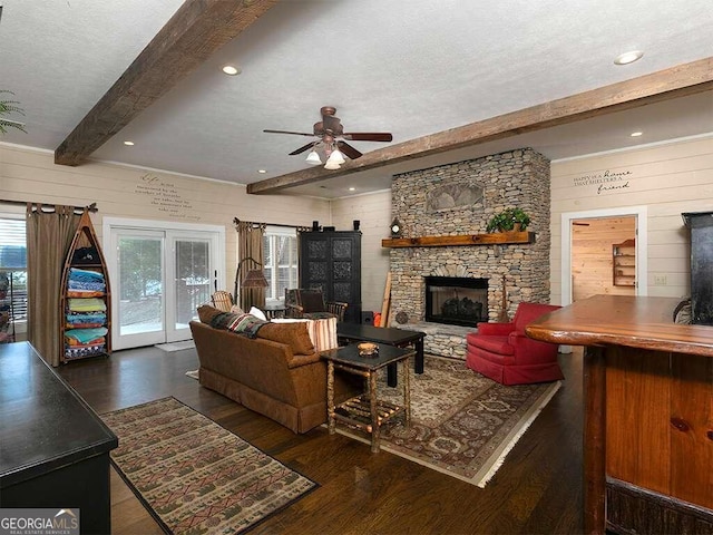 living room with a fireplace, dark hardwood / wood-style floors, ceiling fan, beam ceiling, and a textured ceiling