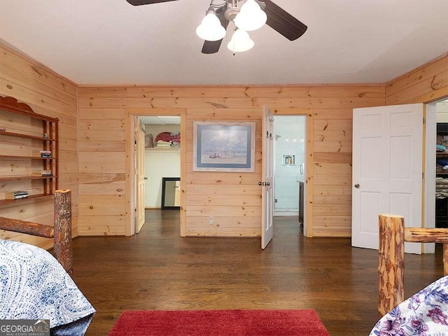 bedroom with dark wood-type flooring, ceiling fan, and wooden walls