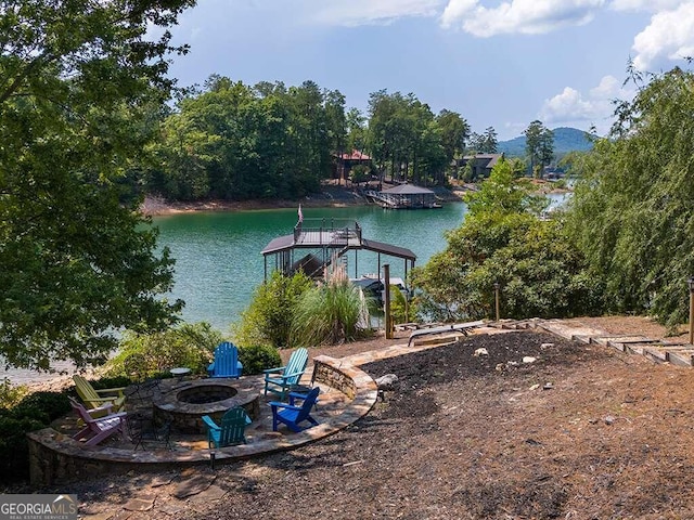 view of dock with a water view and a fire pit