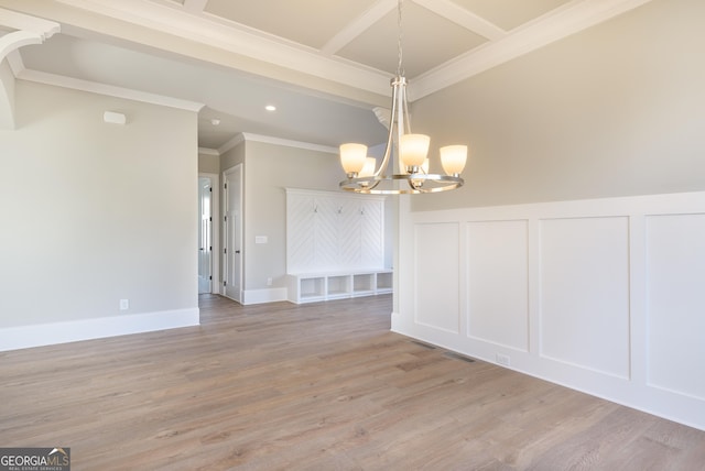 spare room with an inviting chandelier, light hardwood / wood-style flooring, and ornamental molding