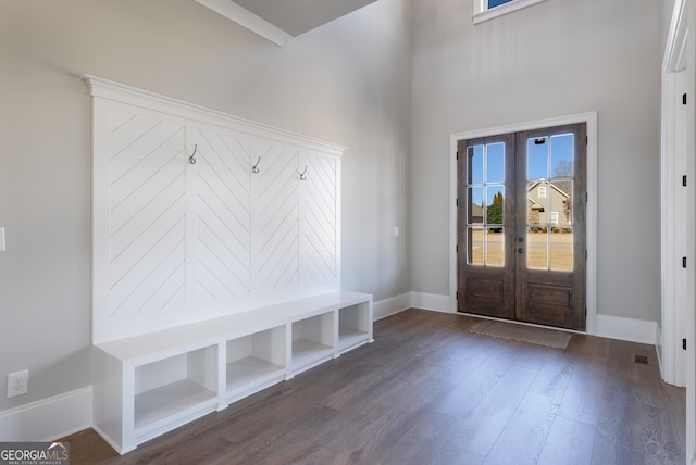 mudroom with dark wood-type flooring, a towering ceiling, and french doors