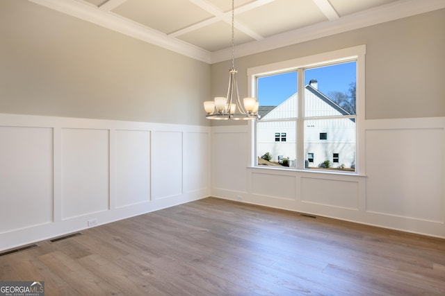 unfurnished dining area with crown molding, beam ceiling, coffered ceiling, a notable chandelier, and light wood-type flooring