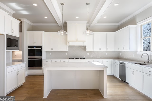 kitchen with beamed ceiling, a kitchen island, sink, and stainless steel appliances