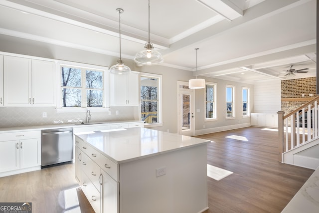 kitchen featuring a kitchen island, sink, white cabinets, hanging light fixtures, and stainless steel dishwasher