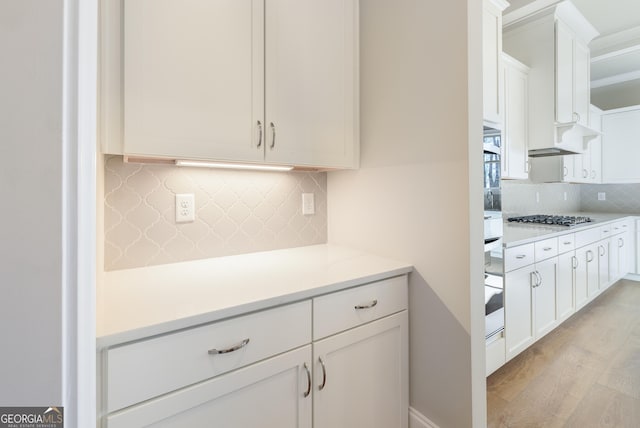 kitchen featuring white cabinetry, stainless steel gas cooktop, light hardwood / wood-style flooring, and decorative backsplash