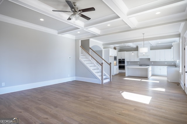 unfurnished living room featuring sink, ceiling fan, coffered ceiling, light hardwood / wood-style floors, and beamed ceiling