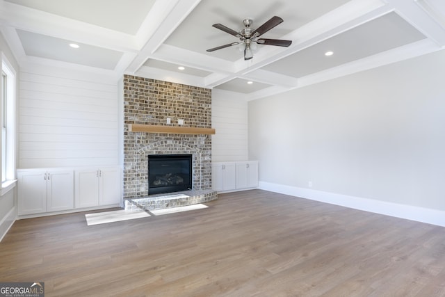 unfurnished living room featuring light hardwood / wood-style flooring, ceiling fan, beam ceiling, coffered ceiling, and a brick fireplace