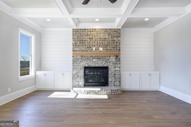 unfurnished living room featuring beam ceiling, ceiling fan, a brick fireplace, and dark hardwood / wood-style flooring