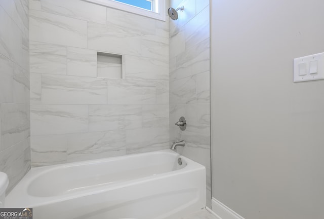 bathroom featuring toilet and tiled shower / bath