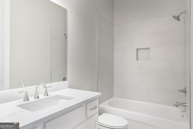 full bathroom featuring tiled shower / bath, vanity, and toilet