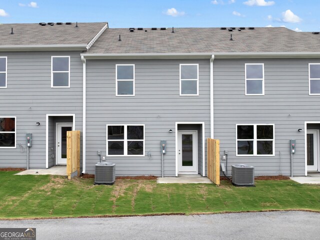 back of property with central air condition unit, a patio area, and a yard