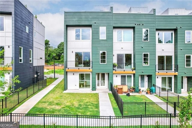 rear view of house featuring a balcony and a yard