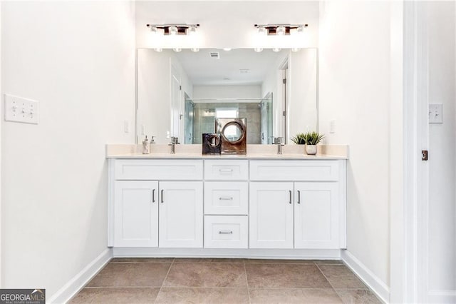 full bath with double vanity, baseboards, a stall shower, and a sink