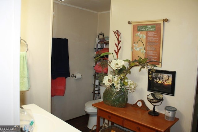 bathroom featuring ornamental molding and toilet