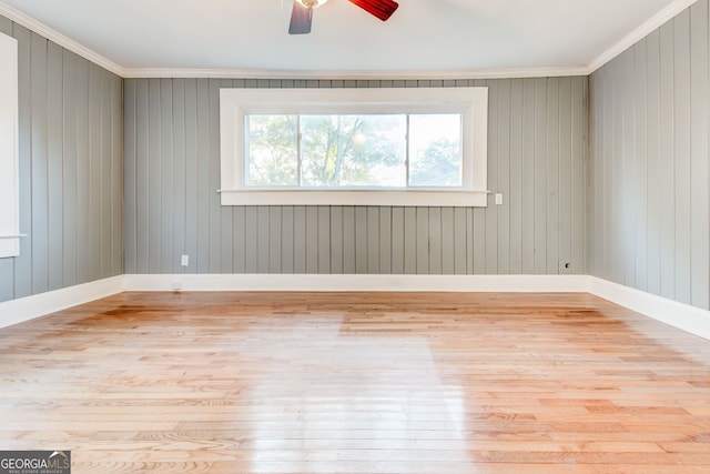 unfurnished room with light wood-type flooring, ceiling fan, crown molding, and wood walls