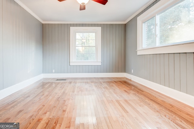 empty room with ornamental molding, a healthy amount of sunlight, and light hardwood / wood-style flooring