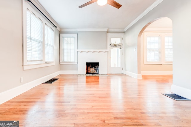 unfurnished living room with ceiling fan, light wood-type flooring, and ornamental molding