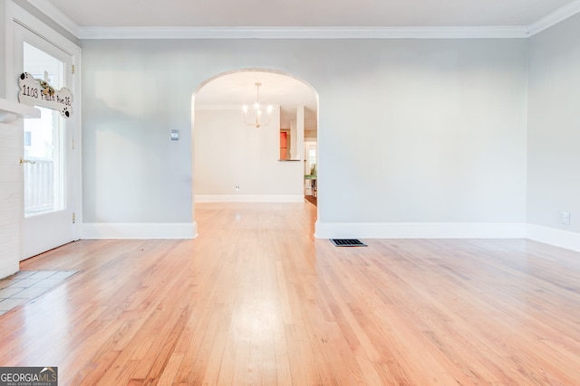 unfurnished room featuring a chandelier, light wood-type flooring, and ornamental molding