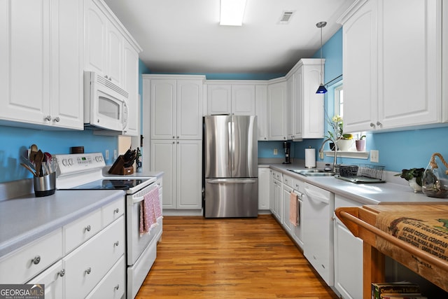 kitchen featuring a sink, visible vents, white appliances, and white cabinets