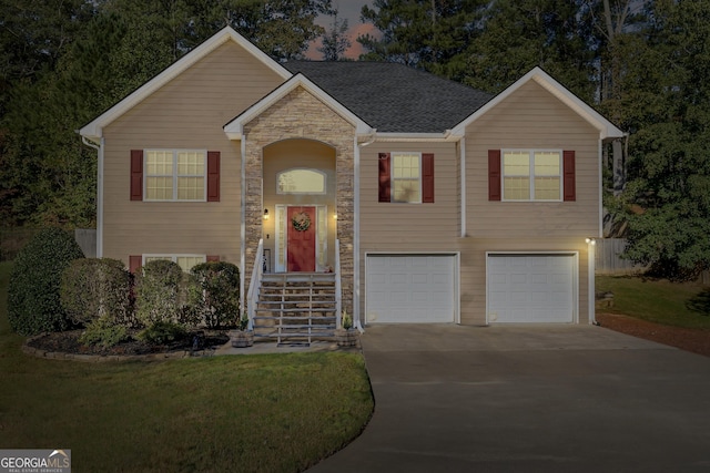 split foyer home featuring a garage, stone siding, driveway, and a shingled roof