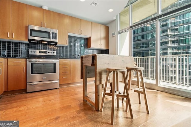 kitchen featuring stainless steel appliances, backsplash, and light hardwood / wood-style floors