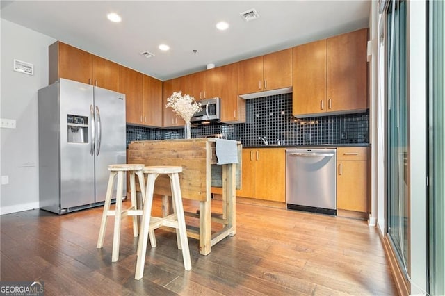 kitchen featuring appliances with stainless steel finishes, light hardwood / wood-style floors, and backsplash