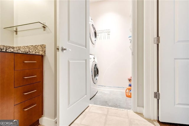 washroom with stacked washer and dryer and light tile patterned floors