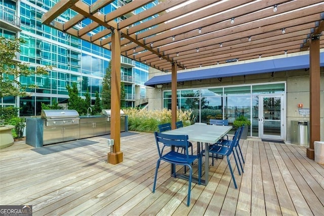 wooden deck featuring area for grilling, sink, a pergola, and an outdoor kitchen