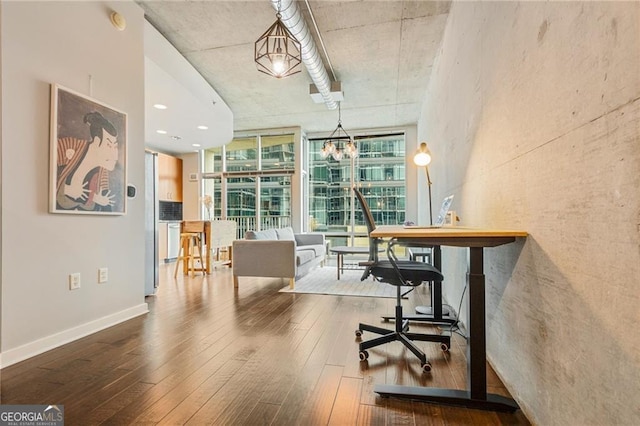 office with expansive windows, an inviting chandelier, and hardwood / wood-style floors