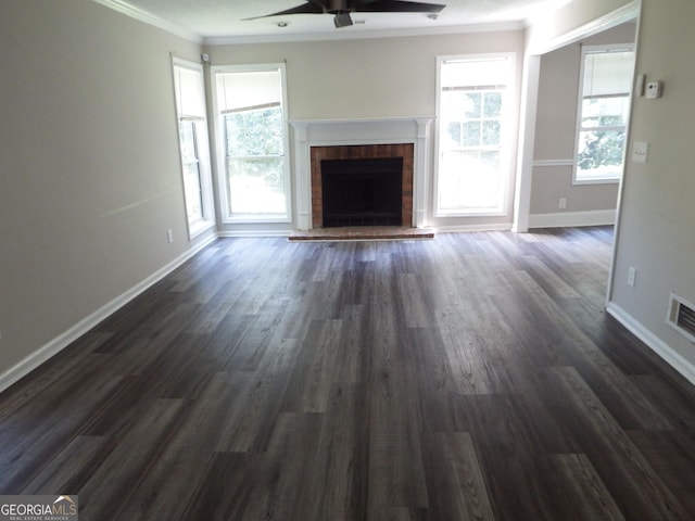 unfurnished living room with a wealth of natural light, a fireplace, crown molding, and dark wood-style flooring