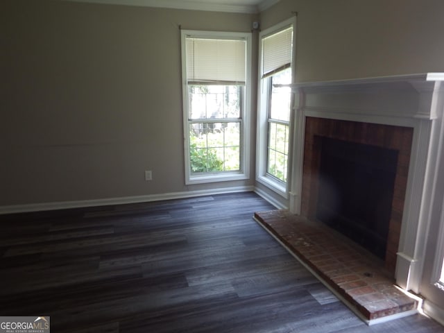 unfurnished living room with dark wood-style floors, baseboards, and a fireplace with raised hearth